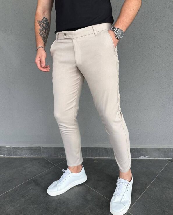 Model u elegantnim muškim pantalonama u bež boji slim kroja sa crnom majicom i belim patikama