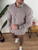 Bež prugasta muška lanena košulja sa khaki pantalonama na svetlom drvenom podu