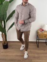 Bež prugasta muška lanena košulja sa khaki pantalonama i pogledom u stranu