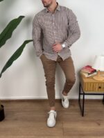 Bež prugasta muška lanena košulja, model okrenut blago u stranu sa rukama uz telo