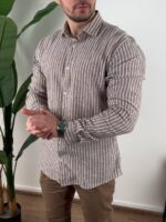 Krem prugasta muška lanena košulja ispred zelene biljke u opuštenom držanju