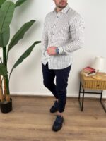 Bela prugasta muška lanena košulja, model sa rukom u džepu pantalona