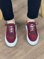 Bordo muške kožne patike sa belim đonom u niskom kadru, kombinovane sa crnim pantalonama