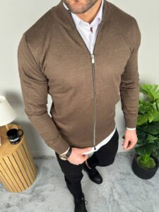 Muški braon džemper sa zipom u frontalnom kadru, model u beloj košulji i crnim pantalonama