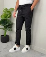 Model u crnim muškim pantalonama sa lastišem pored zelene saksijske biljke