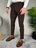 Braon elegantne pantalone u celoj figuri, model stoji ravno, vidi se pad nogavica do gležnja