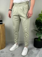 Detalj prednje strane svetlo zelenih pantalona sa podesivim pojasom i metalnom kopčom