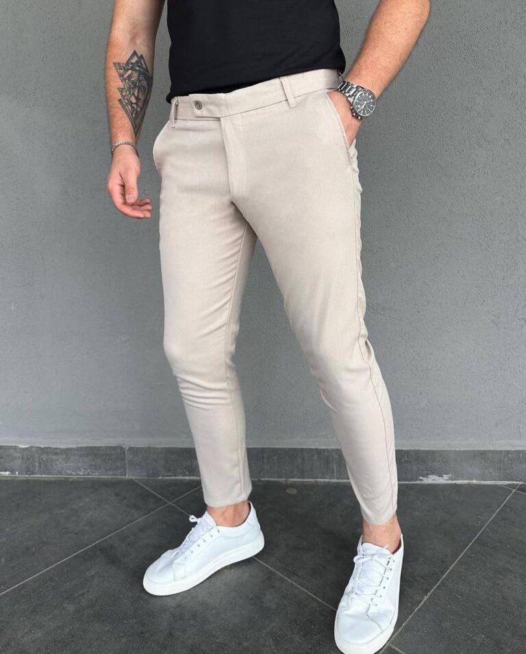 Model u elegantnim muškim pantalonama u bež boji slim kroja sa crnom majicom i belim patikama