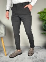 Elegantne tamnosive muške pantalone sa rukom u prednjem džepu i naglašenom slim siluetom