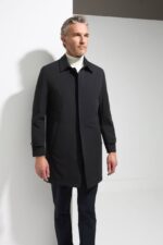 Crni elegantni zimski mantil od vodoodbojnog materijala na modelu uz belu rolku, frontalni kadar