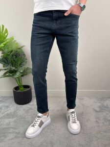 Slim fit muške farmerke tamnoplave boje iz prednjeg ugla sa belim patikama u kadru