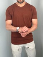 Muška pamučna majica bakreno crvena, model okrenut blago u stranu pridržava sat na zglobu