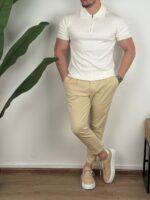 Muška polo majica sa zipom u beloj, model okrenut malo u stranu, ruka u džepu