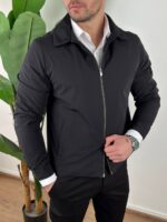Crna muška prelazna jakna two-way zip otvorena na modelu uz crne pantalone