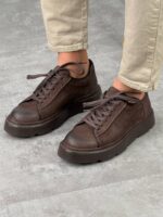 Braon muške kožne cipele Wilson, model čuči pored, beli chunky đon, krem pantalone
