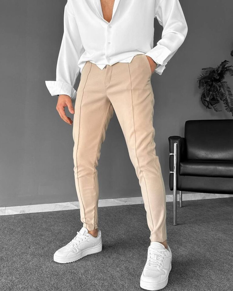 Muške pantalone u bež boji slim kroj, model u beloj košulji s rukom u prednjem džepu