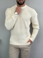 Muški džemper loose fit u krem ekru tonu, model stoji frontalno sa rukom uz vilicu