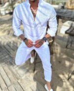 Muški letnji komplet pamučna košulja i pantalone L3874 u beloj boji uz drveni sto na plaži