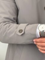 Detalj donjeg dela sivog kišnog mantila sa prošivenom postavom, vidljiva dužina kroja