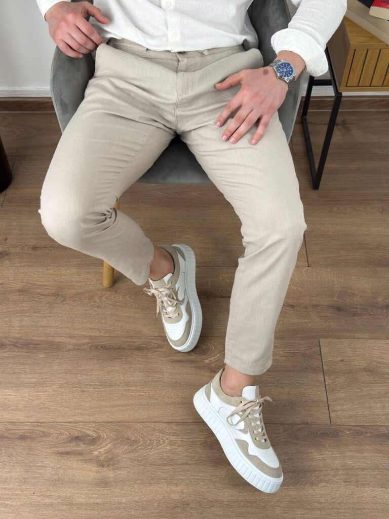 Bež pamučne letnje pantalone na modelu, uži kroj nogavice, frontalni stav uz belu košulju