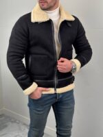 Crna muška zimska jakna sa krznom J1983, model sa rukom u bočnom džepu i denim pantalonama
