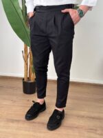 Crne elegantne muške pantalone sa podesivim pojasom, model okrenut leđima sa rukom u džepu