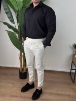 Tri četvrtinski profil modela u krem pantalonama sa podesivim pojasom kraj stolice
