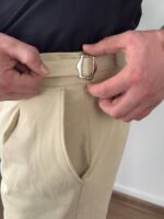 Maslinasto zelene elegantne muške pantalone sa podesivim pojasom, prednji kadar sa belim zidom