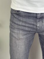 Krupni detalj prednjeg džepa i sive denim teksture klasičnih muških farmerki sa elastinom