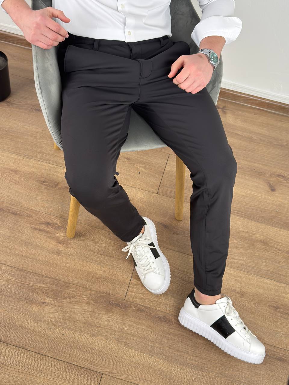 ultra-flex-pantalone-svetlo-crne-p2621-01-slika-1-glavna Ultra flex pantalone crne boje na modelu u sedećoj pozi sa belim patikama